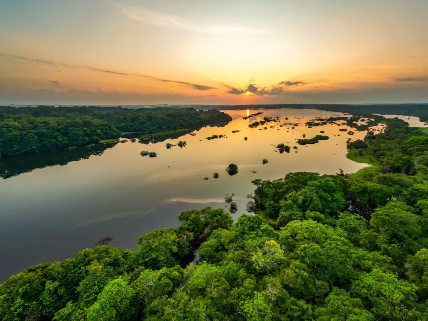 Pôr do sol sobre rio largo cercado por floresta